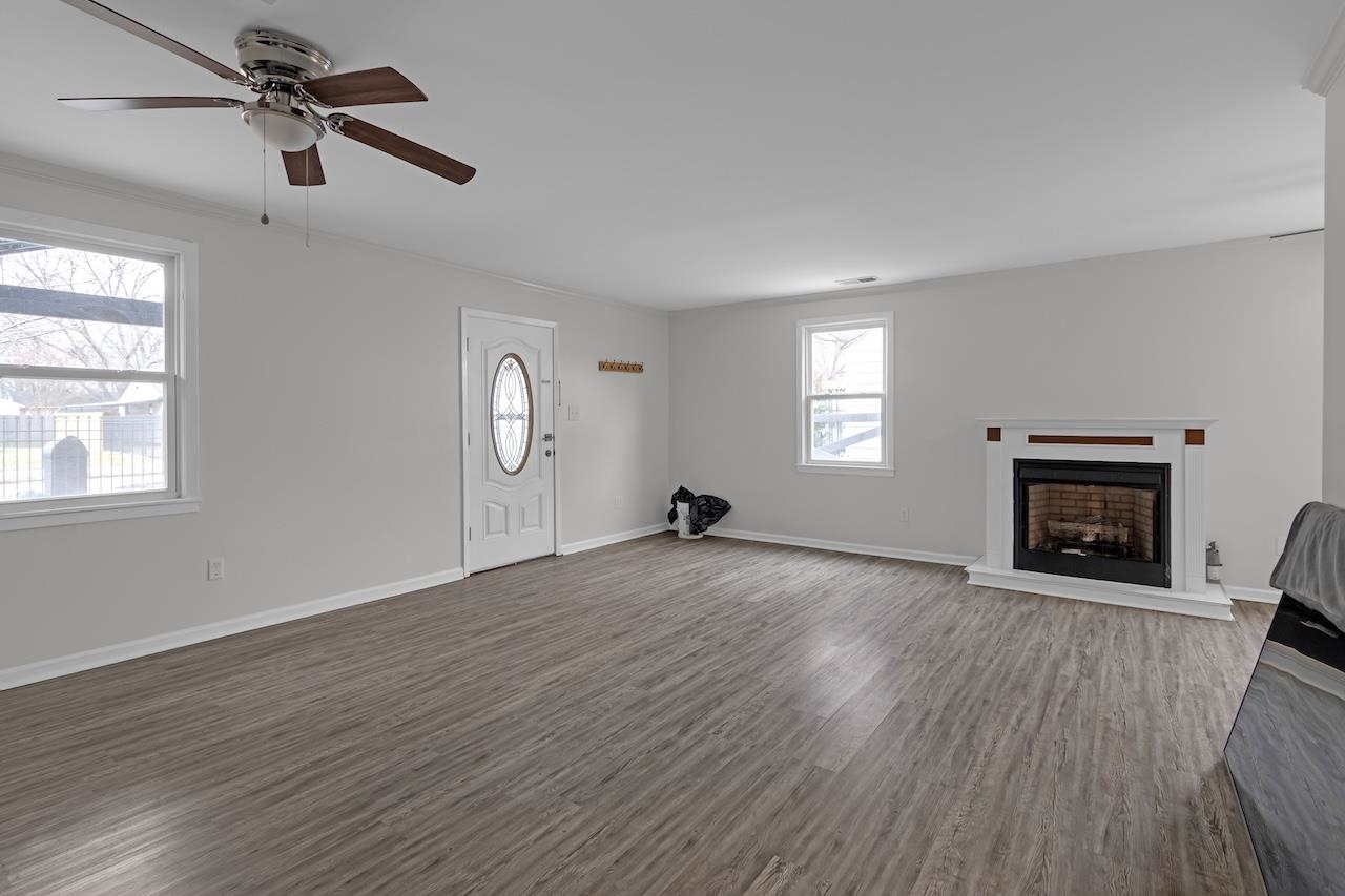 4251 Riviera Drive Memphis, TN 38108 - Photo 5 of 16 an empty room with windows fireplace and wooden floor