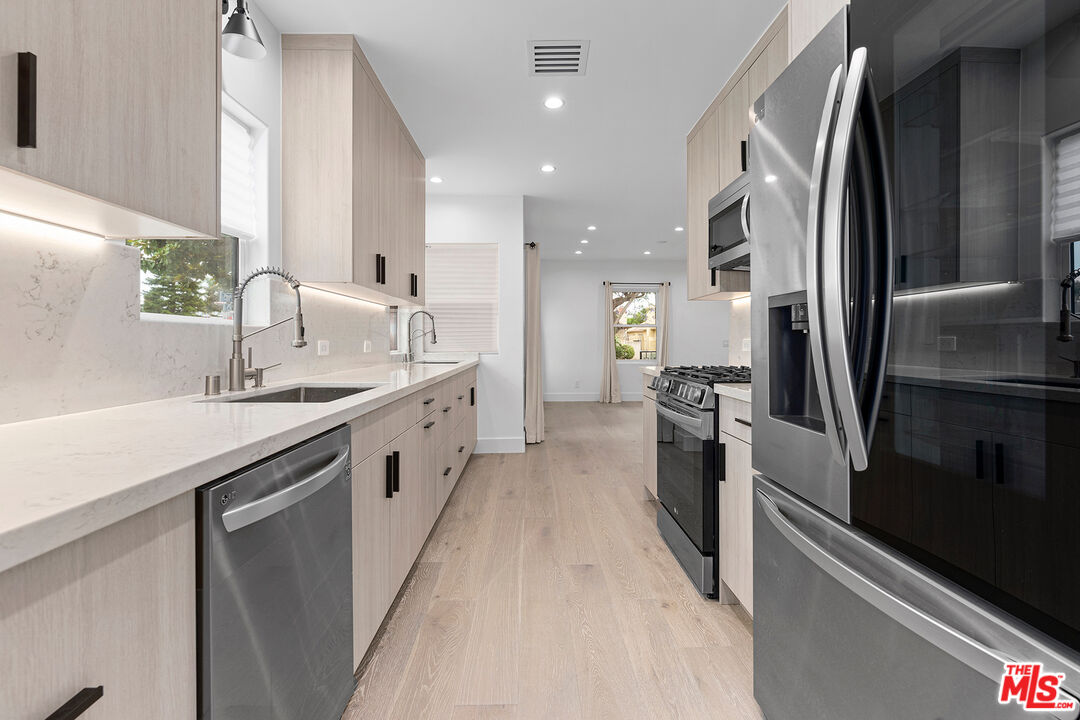 1901 South Point View Street Los Angeles, CA 90034 - Photo 8 of 21 a large kitchen with a large counter top a sink and stainless steel appliances