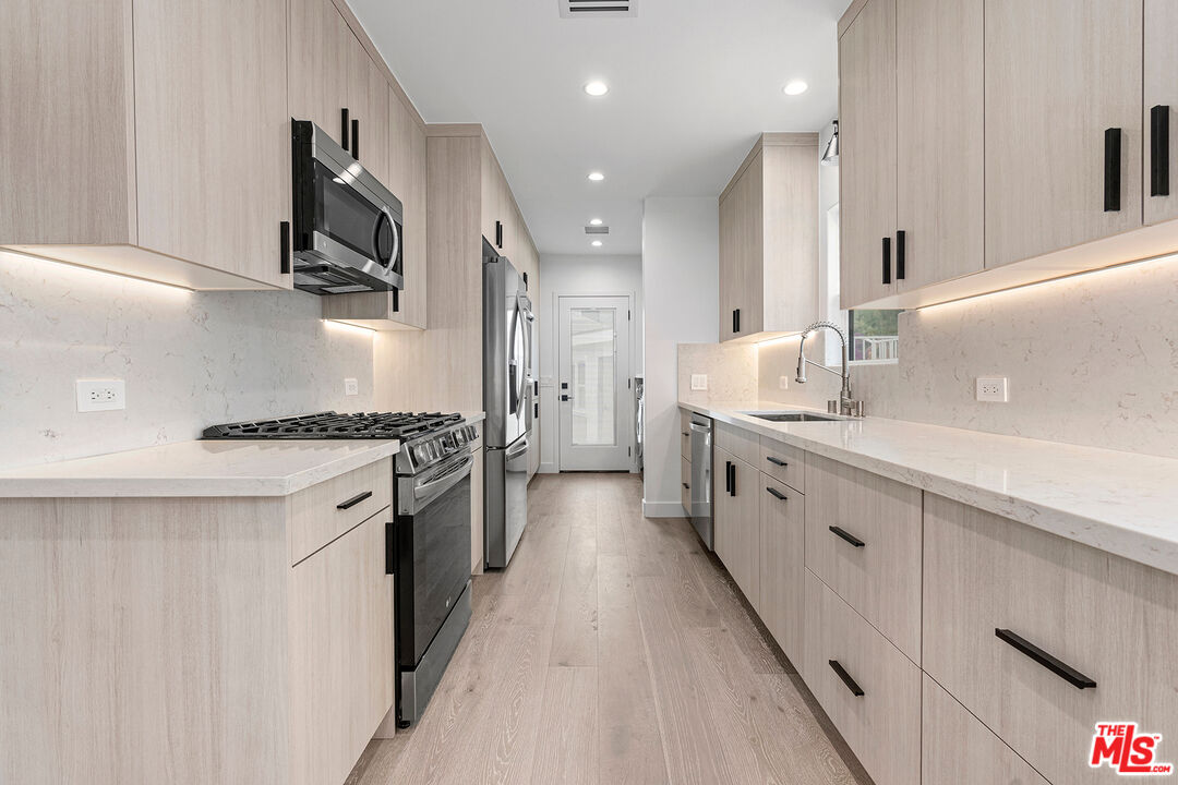 1901 South Point View Street Los Angeles, CA 90034 - Photo 10 of 21 a kitchen with stainless steel appliances a sink stove top oven and white cabinets