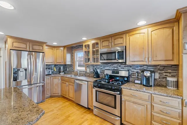 a kitchen with stainless steel appliances granite countertop a stove a sink and a refrigerator
