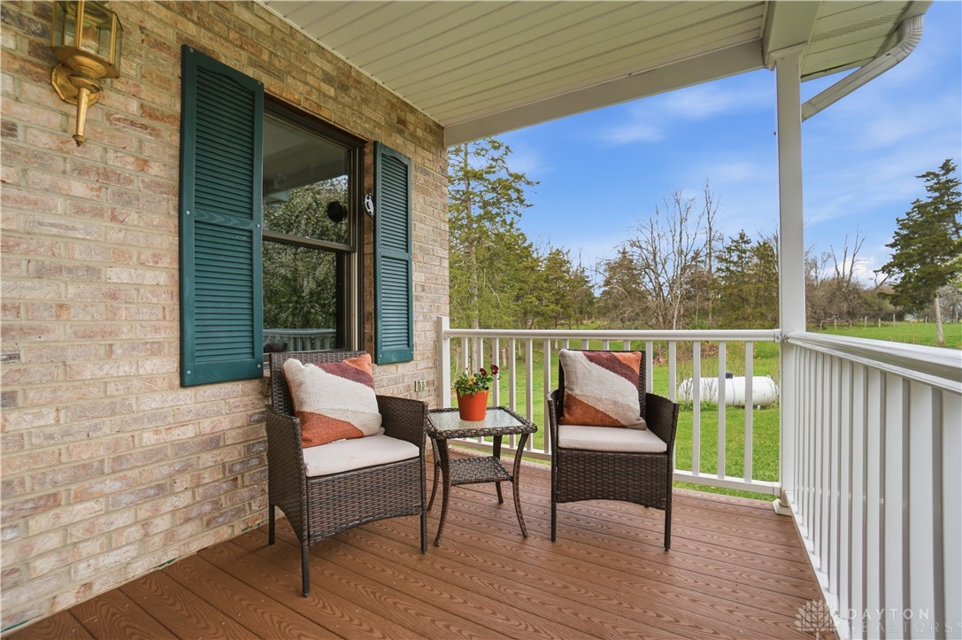 7553 Coffin Station Road Springfield, OH 45502 - Photo 12 of 95 Relax on this charming covered porch, offering serene views of the expansive landscape.
