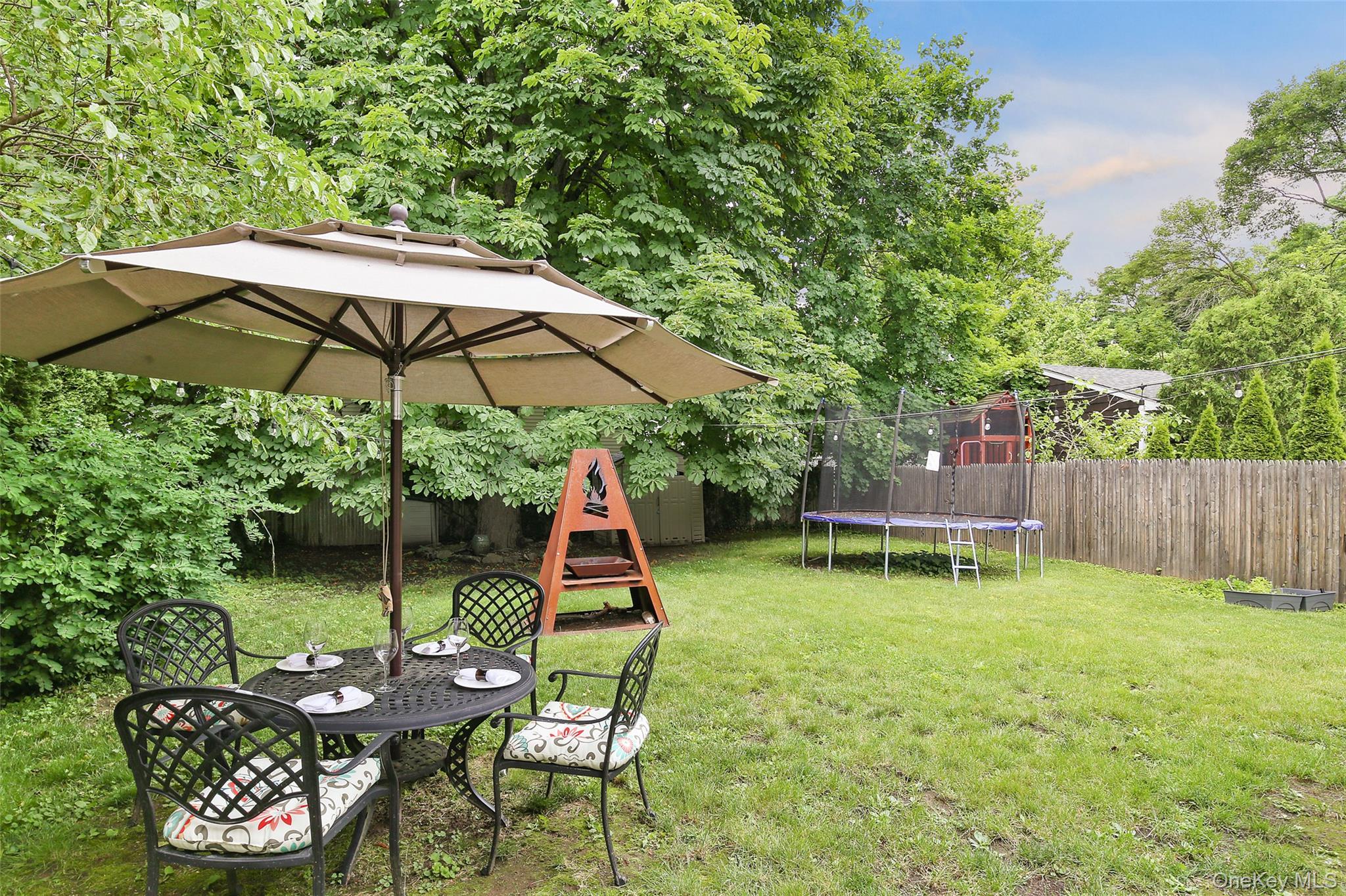 8 Goldwin Street Rye, NY 10580 - Photo 19 of 25 a backyard of a house with table and chairs under an umbrella