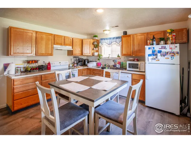 a kitchen with stainless steel appliances a dining table chairs refrigerator and sink