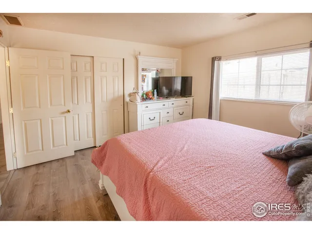a bedroom with a large bed a flat tv screen and a window