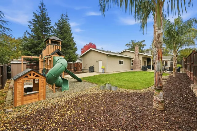 a kitchen with stainless steel appliances granite countertop a table chairs in it and wooden floors