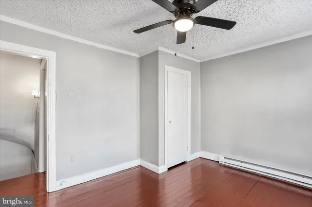 an empty room with wooden floor chandelier fan and windows