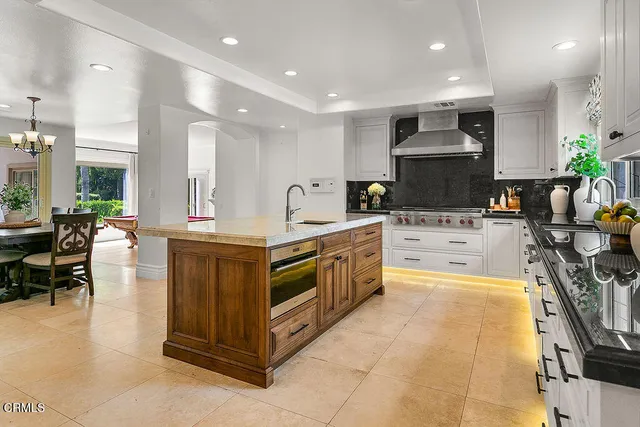 a large kitchen with stainless steel appliances kitchen island granite countertop a refrigerator and a stove top oven