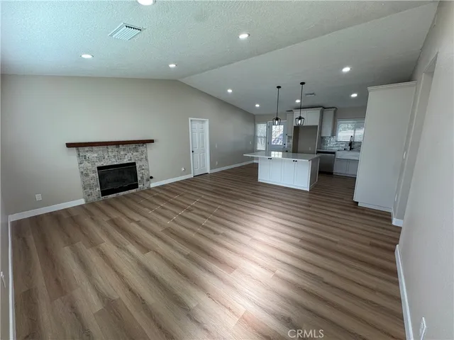 an open kitchen view with fireplace and wooden floor