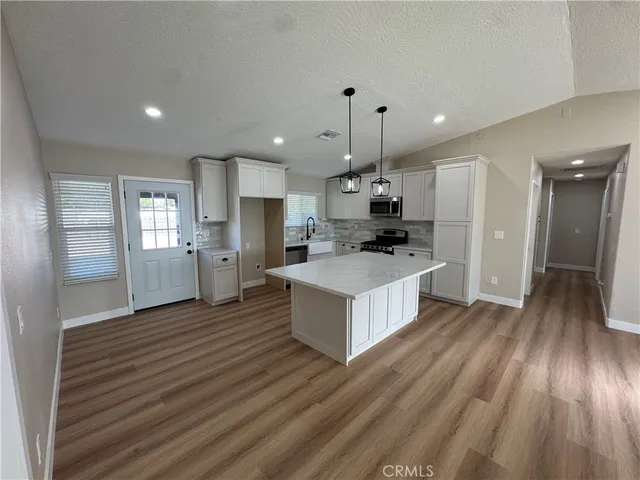 a large kitchen with kitchen island a island wooden floor stainless steel appliances and white cabinets