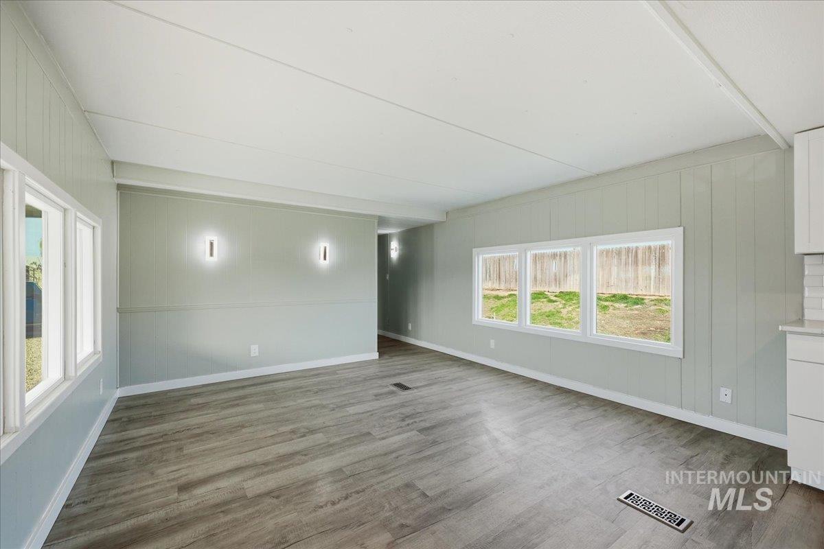 5015 East Ustick Road, Unit 172 Caldwell, ID 83605 - Photo 12 of 21 Unfurnished room featuring wooden walls, dark wood-type flooring, and beamed ceiling