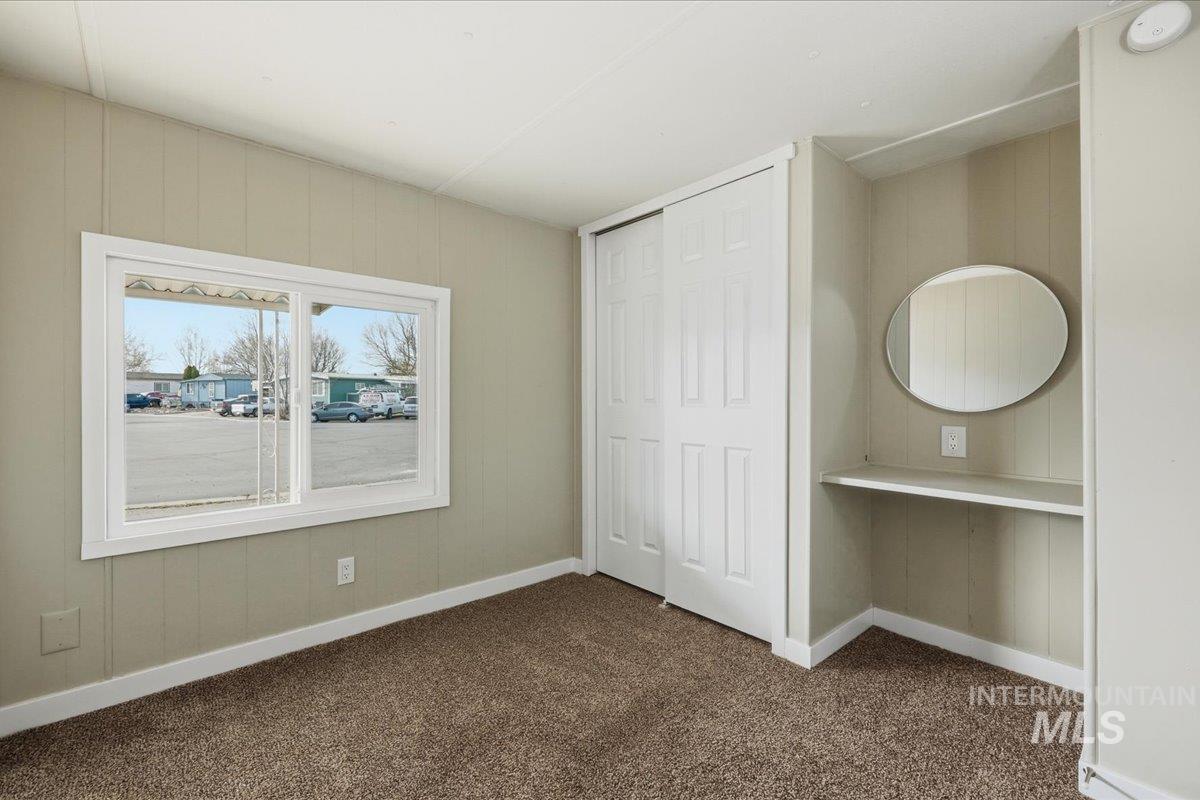 5015 East Ustick Road, Unit 172 Caldwell, ID 83605 - Photo 14 of 21 Unfurnished bedroom featuring wood walls, dark carpet, and a closet