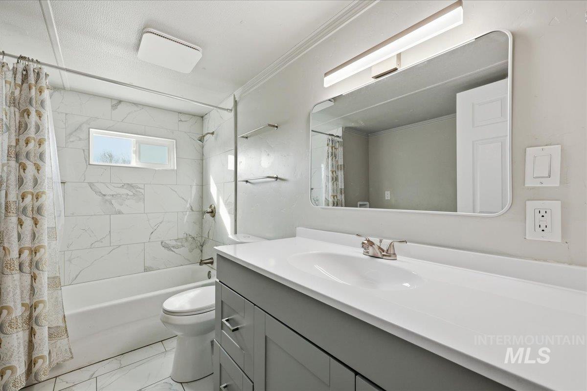 5015 East Ustick Road, Unit 172 Caldwell, ID 83605 - Photo 15 of 21 Bathroom featuring vanity, shower / bath combo with shower curtain, light marble finish floors, and ornamental molding