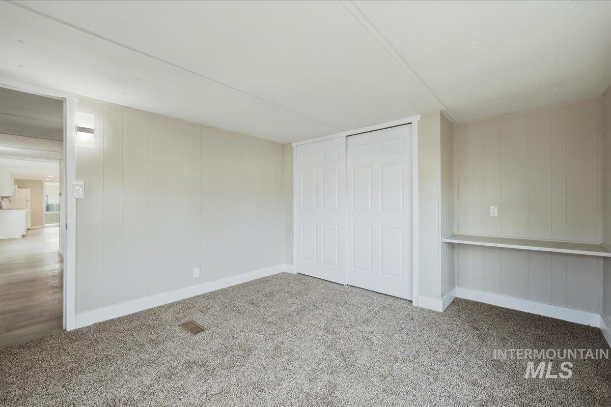 5015 East Ustick Road, Unit 172 Caldwell, ID 83605 - Photo 18 of 21 Unfurnished bedroom featuring light carpet, a closet, and wooden walls