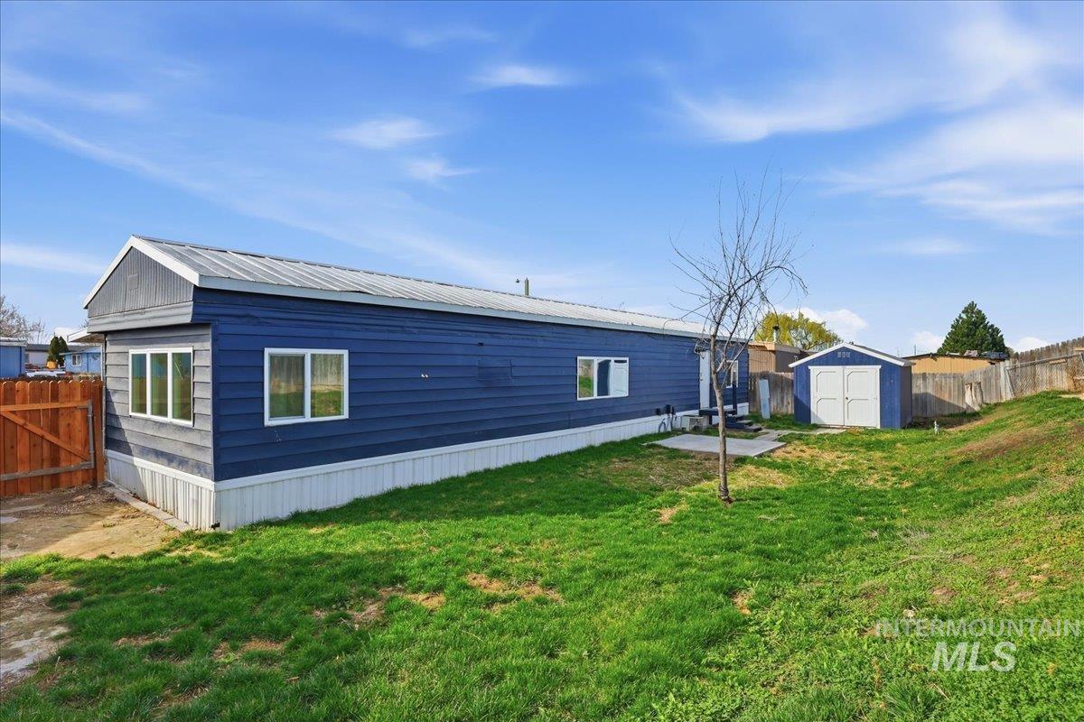 5015 East Ustick Road, Unit 172 Caldwell, ID 83605 - Photo 20 of 21 Rear view of property with a fenced backyard, a metal roof, a shed, and a patio