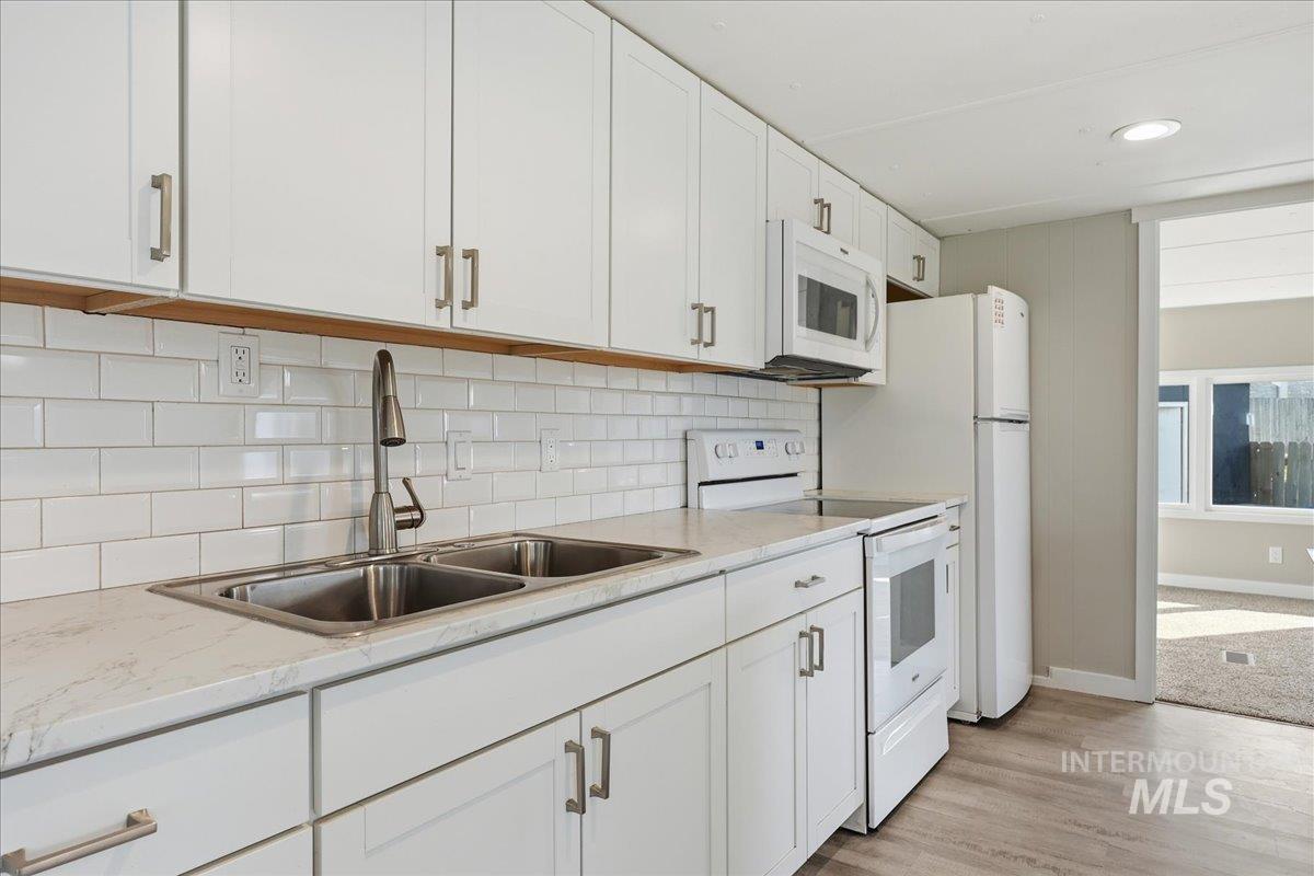 5015 East Ustick Road, Unit 172 Caldwell, ID 83605 - Photo 6 of 21 Kitchen with white appliances, white cabinetry, decorative backsplash, light wood-style flooring, and light stone countertops