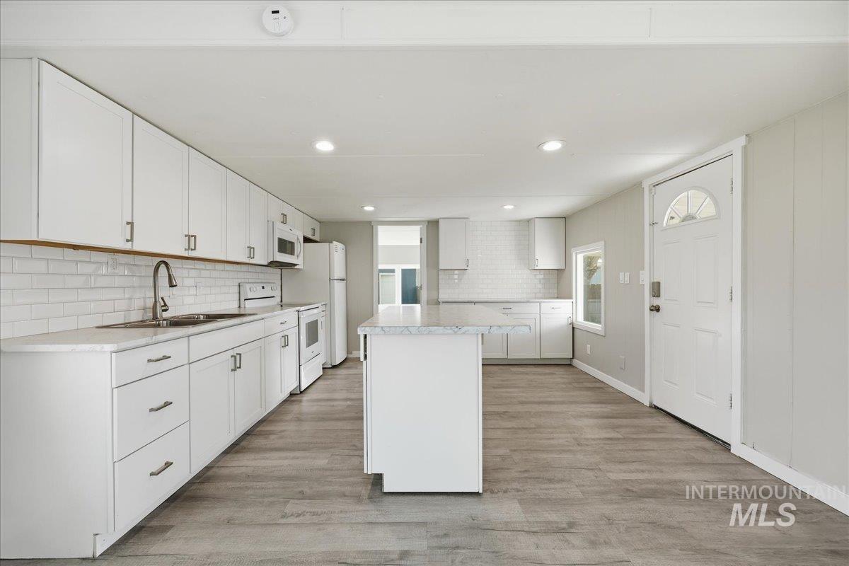 5015 East Ustick Road, Unit 172 Caldwell, ID 83605 - Photo 7 of 21 Kitchen with light countertops, white cabinetry, white appliances, tasteful backsplash, and a kitchen island