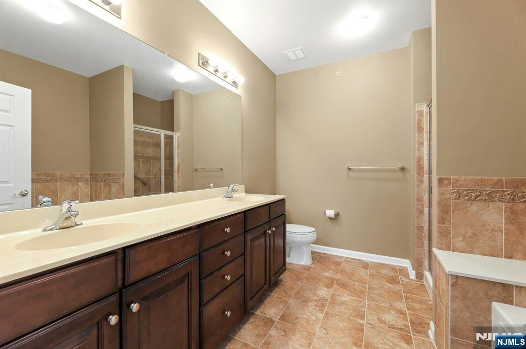 6 Cliff Road, Unit D2 Woodland Park, NJ 07424 - Photo 17 of 40 a bathroom with a double vanity sink toilet and a mirror