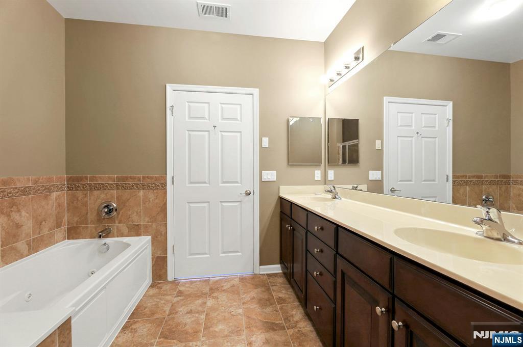 6 Cliff Road, Unit D2 Woodland Park, NJ 07424 - Photo 19 of 40 a spacious bathroom with a tub sink shower and mirror