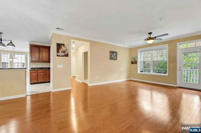 a view of an empty room with window and wooden floor