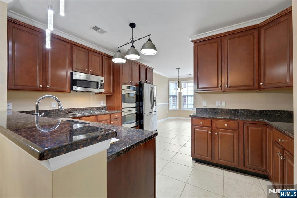 6 Cliff Road, Unit D2 Woodland Park, NJ 07424 - Photo 10 of 40 a kitchen with kitchen island granite countertop a sink a counter top space cabinets and stainless steel appliances