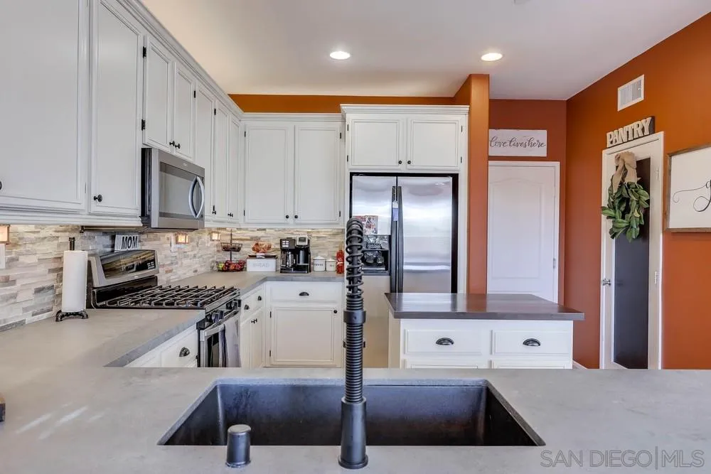 10005 Day Creek Trail Santee, CA 92071 - Photo 20 of 45 a kitchen with stainless steel appliances granite countertop a refrigerator a stove and white cabinets with wooden floor
