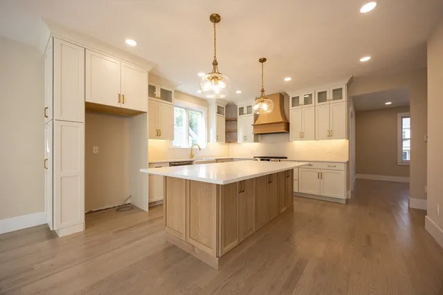 a large kitchen with a large counter top a sink stainless steel appliances and cabinets