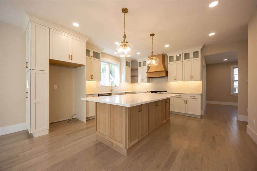 a large kitchen with a large counter top a sink stainless steel appliances and cabinets