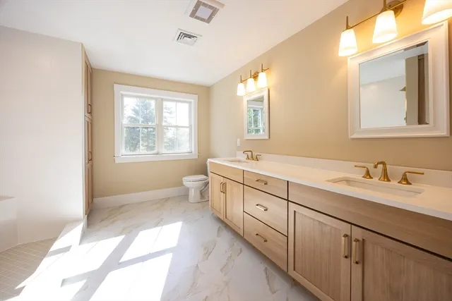 a bathroom with double vanity sink a mirror a window and vanity