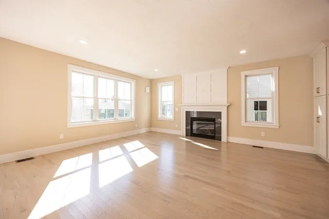 an empty room with windows and fireplace