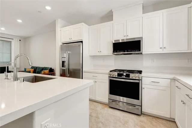 a kitchen with stainless steel appliances a white stove top oven a refrigerator and white cabinets