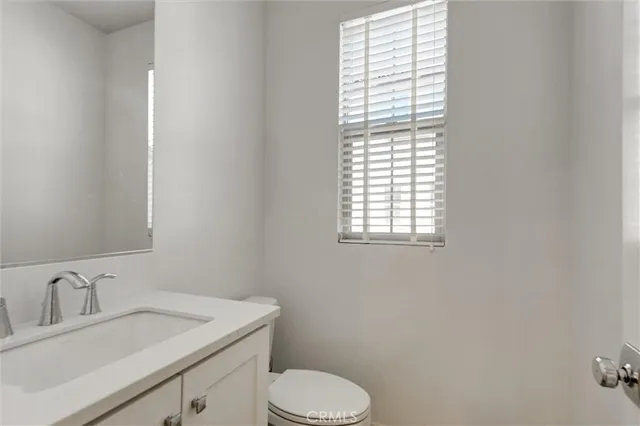 a bathroom with a toilet sink vanity and mirror