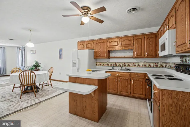 a kitchen with a refrigerator a sink dishwasher a stove and a dining table with wooden floor