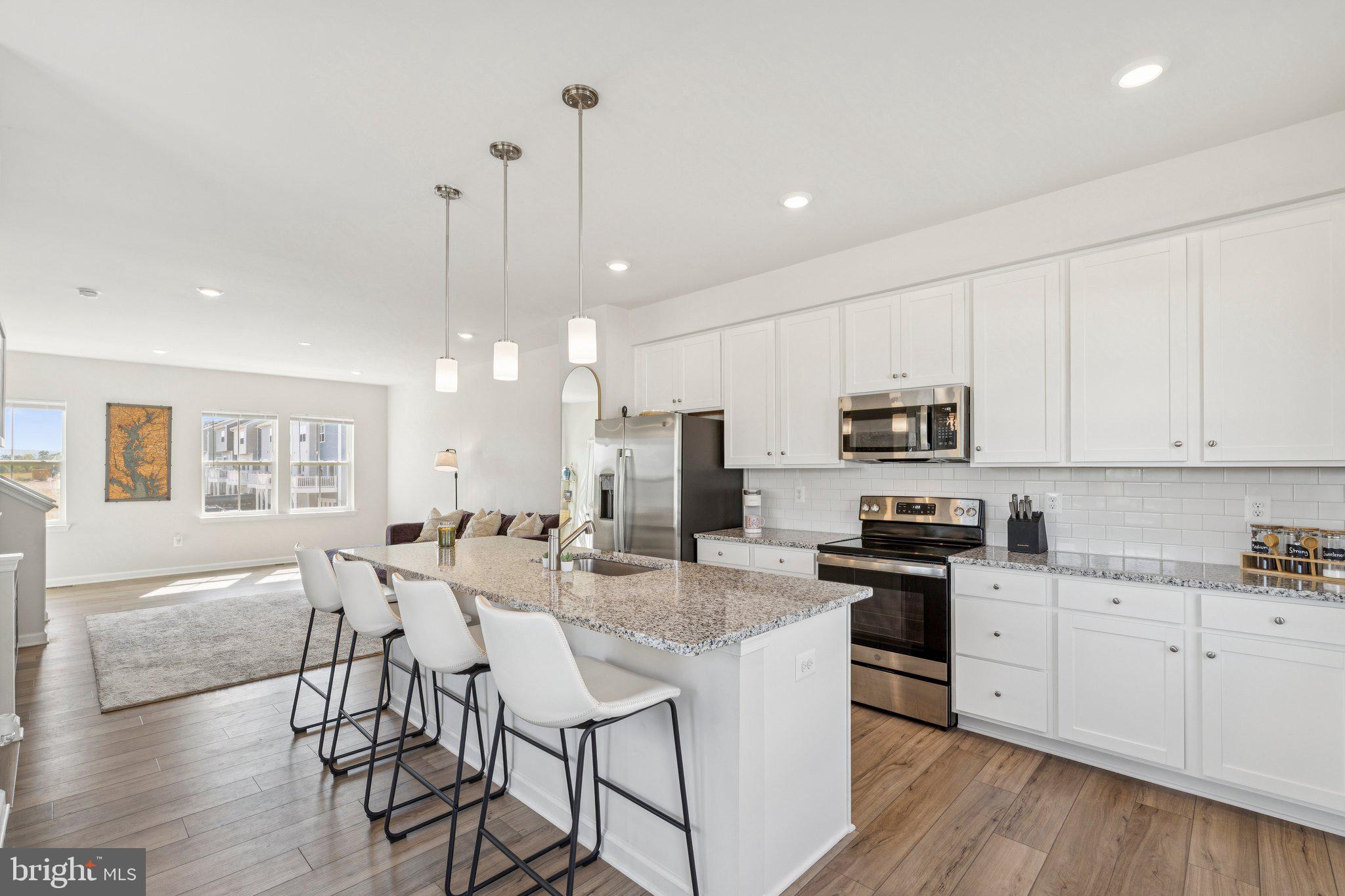 79 Swan Fld Avenue Ranson, WV 25438 - Photo 3 of 22 a kitchen with stainless steel appliances kitchen island granite countertop a stove a sink a refrigerator a stove a dining table and chairs with wooden floor