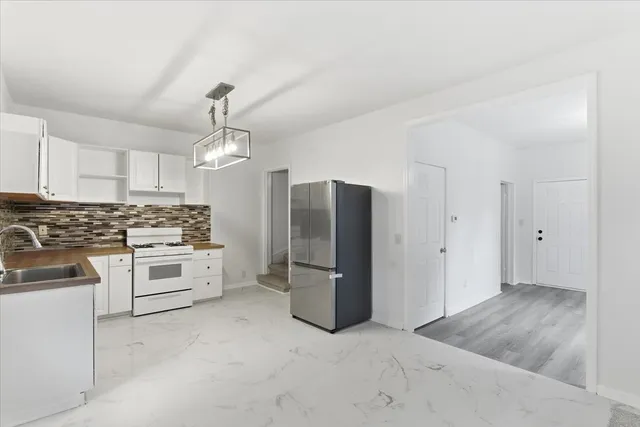 a kitchen with stainless steel appliances kitchen island granite countertop a refrigerator oven a sink with dishwasher and white cabinets