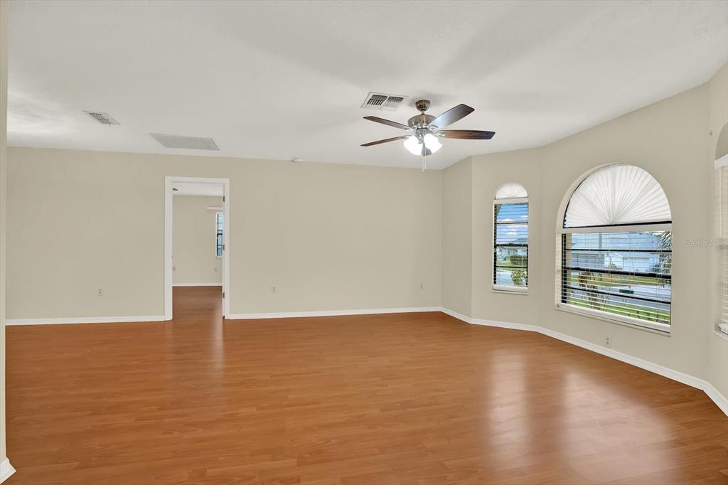1503 Overland Drive Spring Hill, FL 34608 - Photo 4 of 24 an empty room with wooden floor chandelier fan and windows