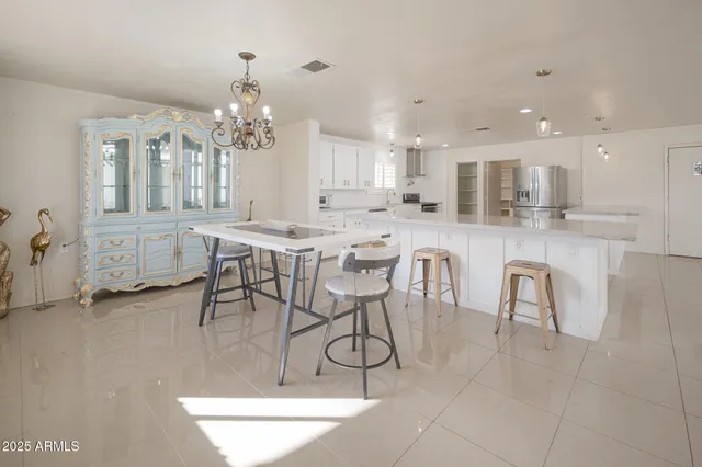 a dining hall with stainless steel appliances granite countertop a table and chairs in it