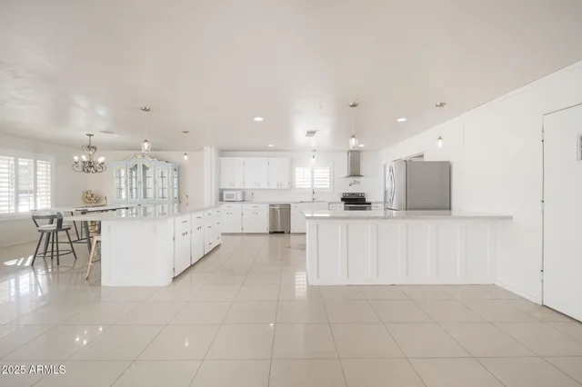 a large white kitchen with kitchen island white cabinets and stainless steel appliances