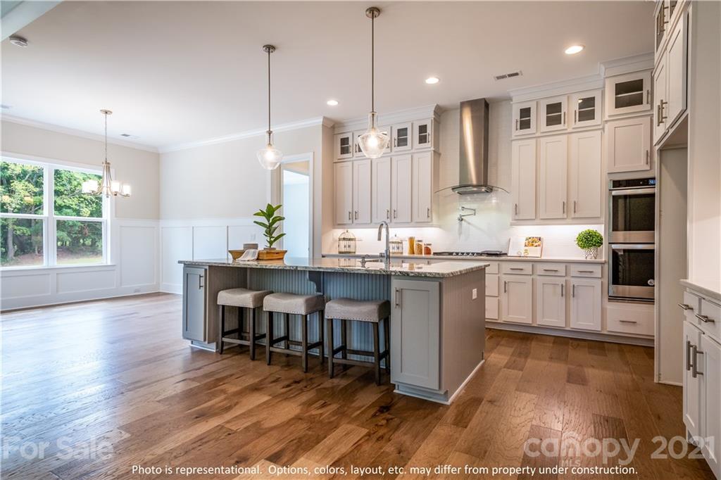 357 Grassy Rdg Court, Unit 50 Clover, SC 29710 - Photo 2 of 27 a kitchen with kitchen island granite countertop a stove a sink a oven a dining table and chairs with wooden floor