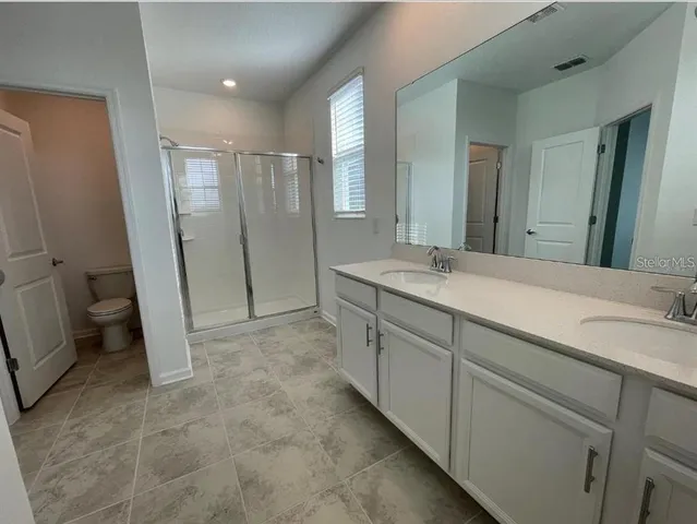 a spacious bathroom with a mirror sink and toilet