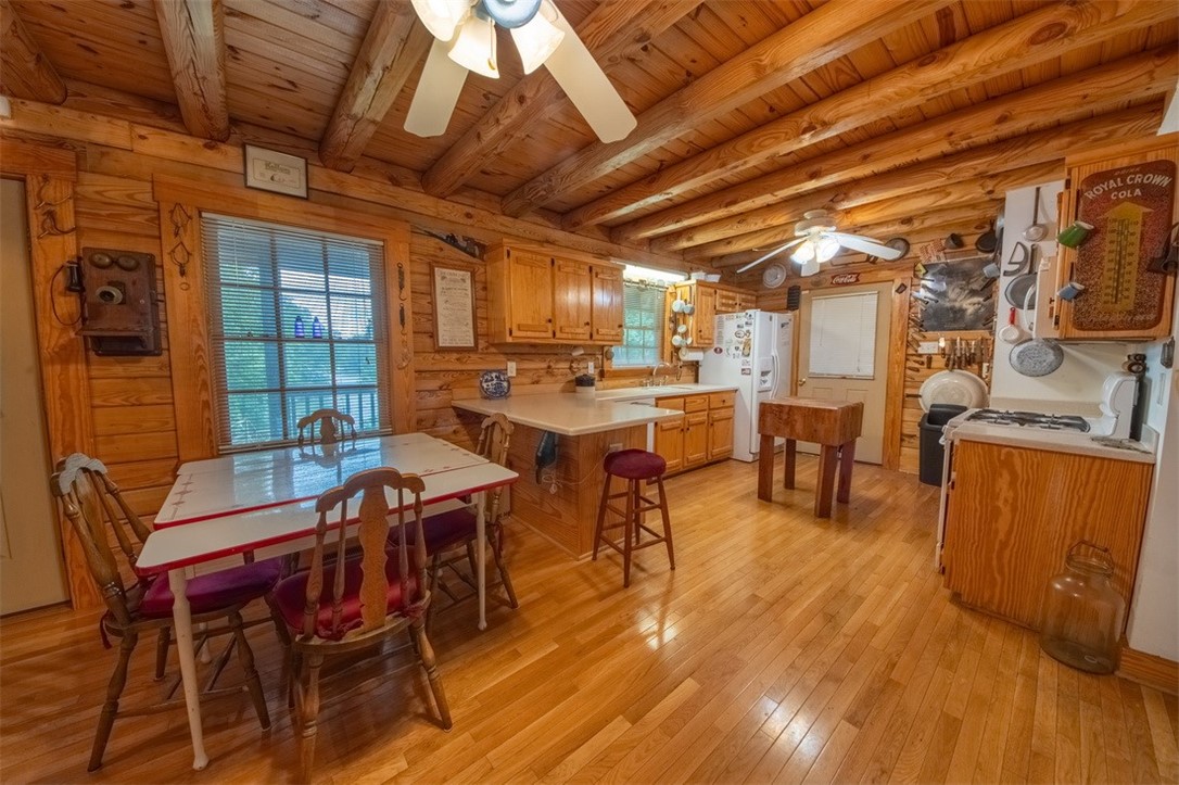 846 Twiggs Ferry Road Hartfield, VA 23071 - Photo 18 of 28 Dining space featuring light wood finished floors, a wood ceiling with exposed beams, a ceiling fan, and wooden walls