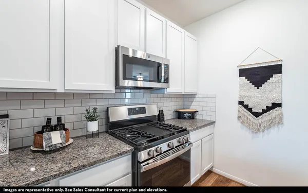a kitchen with granite countertop a stove a microwave and sink