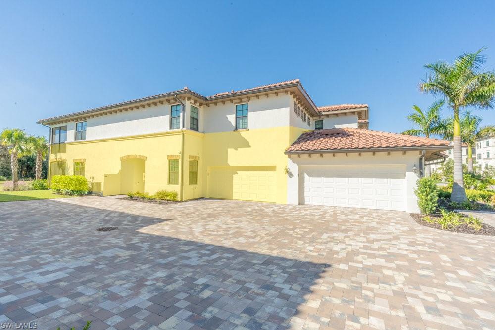 16352 Viansa Way, Unit 10101 Naples, FL 34110 - Photo 26 of 37 a front view of a house with a yard and garage