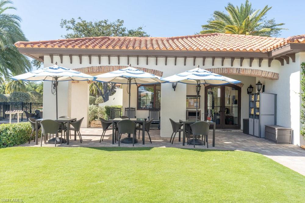 16352 Viansa Way, Unit 10101 Naples, FL 34110 - Photo 31 of 37 a couple of table and chairs under an umbrella