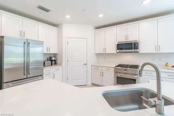 a kitchen with a refrigerator sink and cabinets