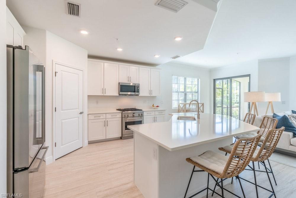 16352 Viansa Way, Unit 10101 Naples, FL 34110 - Photo 6 of 37 a kitchen with stainless steel appliances granite countertop a stove refrigerator sink and cabinets