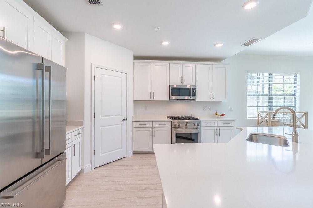 16352 Viansa Way, Unit 10101 Naples, FL 34110 - Photo 7 of 37 a kitchen with cabinets and a refrigerator