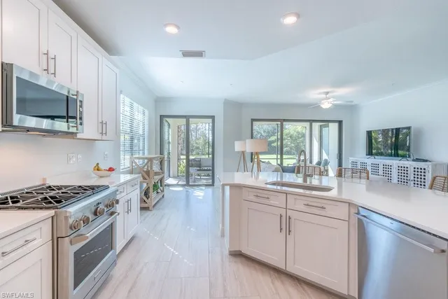 a kitchen with stainless steel appliances white cabinets a sink and a stove