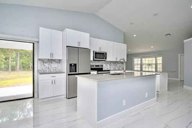 a kitchen with granite countertop a refrigerator and a stove top oven