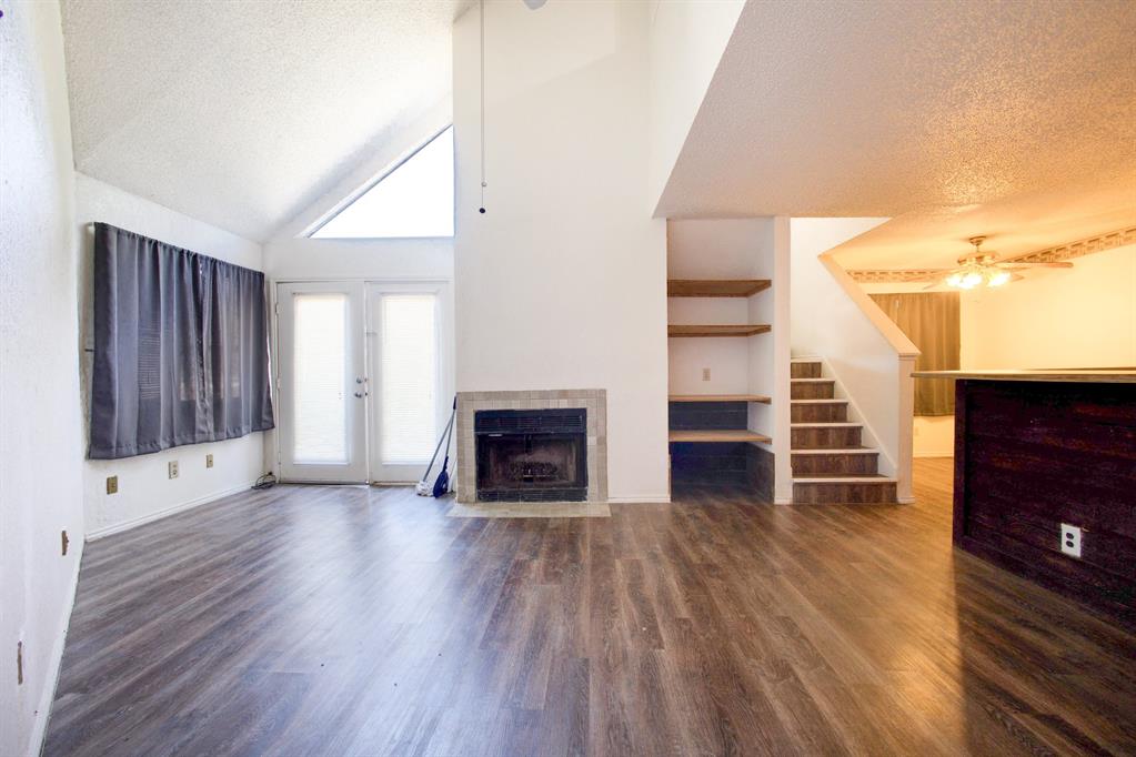 9827 Walnut Street, Unit 210 Dallas, TX 75243 - Photo 17 of 30 an empty room with wooden floor fireplace and staircase