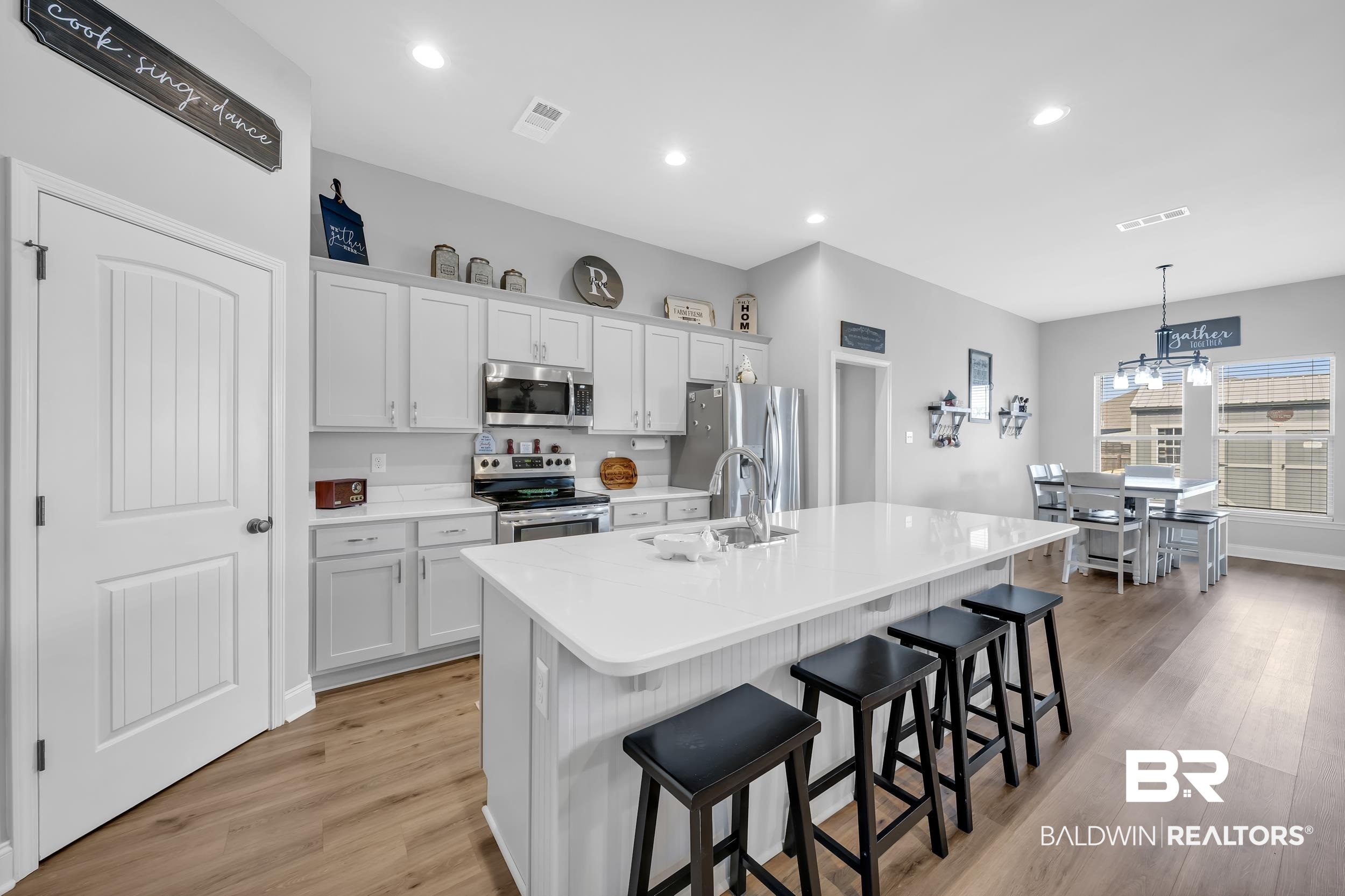 1176 Stella Road Foley, AL 36535 - Photo 13 of 40 Kitchen featuring a breakfast bar, stainless steel appliances, white cabinets, a kitchen island with sink, and light wood finished floors